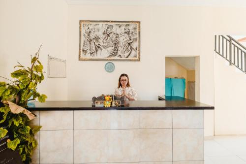 a woman standing behind a counter in a room at Samudra Homestay in Kuta