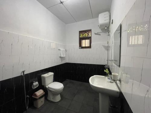 a white bathroom with a toilet and a sink at Villa One Hikkaduwa in Hikkaduwa
