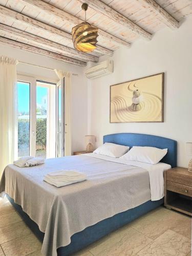 a white bedroom with a blue bed and a window at Villa Magenta in Mikonos