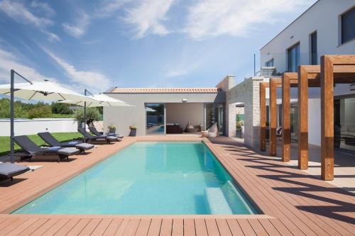 a swimming pool with chairs and a house at Villa Royal Green - Happy Rentals in Labin