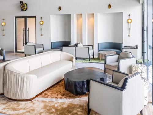 a living room with a white couch and chairs at Bon Hotel Crown Forest in Nsuaem