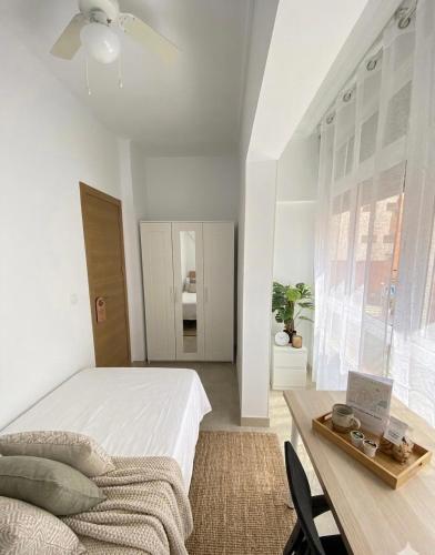 a white bedroom with a bed and a table at Apartamentos SOL y ARENA in Almería