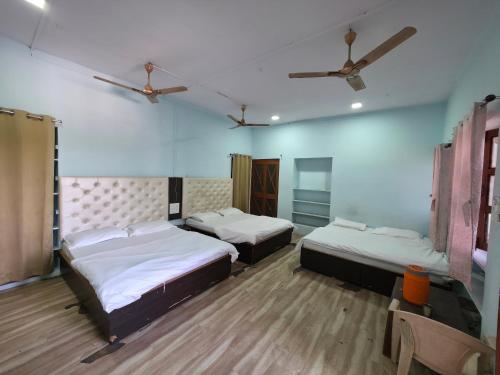 a room with three beds and a ceiling fan at Jodhpur House Mount Abu in Mount Ābu