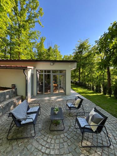 a patio with chairs and a table in front of a house at Woodland Retreat in Ampoiţa