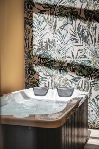 a hot tub in a bathroom with a tropical wallpaper at ATELIER5 Suites in Ermoupoli