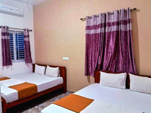 two beds in a room with purple curtains at ARUL Residency in Mettuppālaiyam