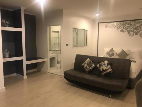 a living room with a black couch and a bathroom at white house in Phangnga
