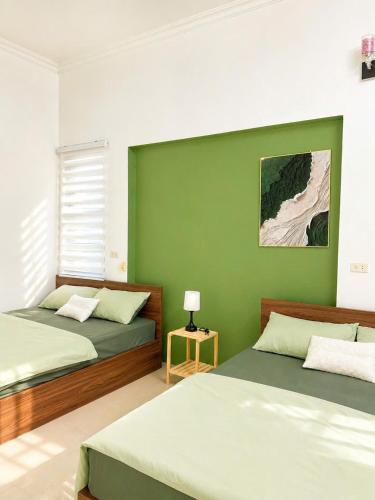a bedroom with two beds and a green wall at Lapausa Homestay in Kỳ Vĩ