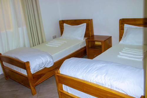 two beds in a room with two night stands at Chama Haven Appartments in Tengeru