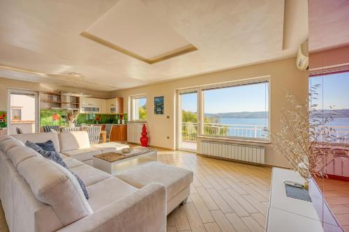 ein Wohnzimmer mit weißem Sofa und großem Fenster in der Unterkunft Debeli Rtič Apartments in Ankaran