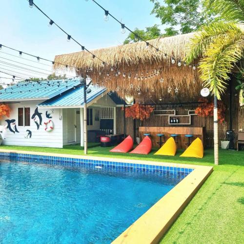 a house with a swimming pool with a thatch roof at Tiki Pool Pattaya in Ban Nong Pla Lai
