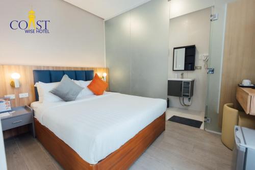 a bedroom with a large bed and a tv at Coast Wise Hotel Dumaguete in Dumaguete