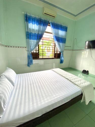 a large white bed in a room with a window at Quốc Khánh Guest House in Thôn Lại Thê