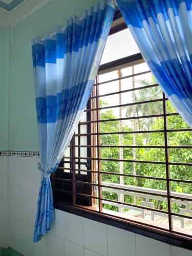 a window with blue curtains in a room at Quốc Khánh Guest House in Thôn Lại Thê
