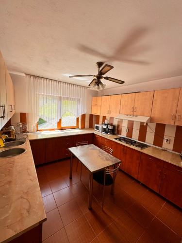 a kitchen with wooden cabinets and a ceiling fan at Pensiunea Emanuel in Gârda de Sus