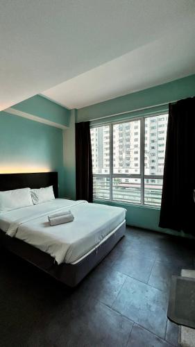 a bedroom with a large bed with two large windows at Bright Hotel in Petaling Jaya