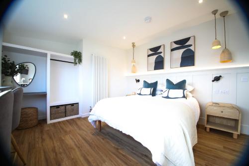 a bedroom with a white bed and a mirror at Abode Above at Tor View in Padstow