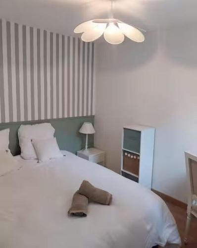 a bedroom with a large white bed with a hat on it at Maison au calme 2 chambres centre de Caen in Caen