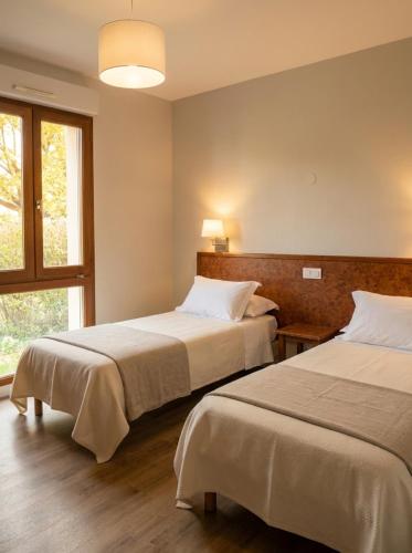 a hotel room with two beds and a window at Hotel La Planquette in Réquista
