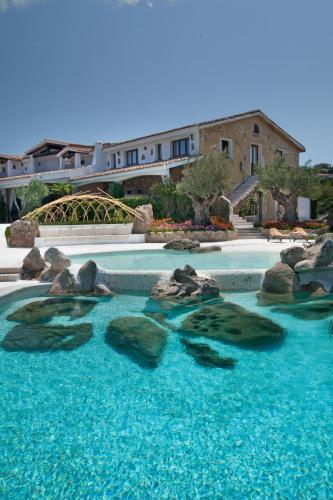 a swimming pool with rocks and blue water at Hotel Pulicinu in Baja Sardinia
