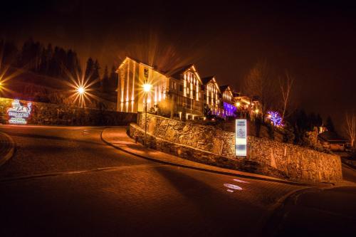 a house with lights on a street at night at Hotel & Medi-Spa Biały Kamień in Świeradów-Zdrój