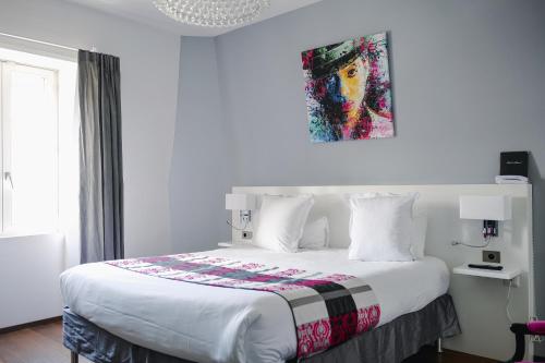 a bedroom with a white bed with a painting on the wall at Le Manoir Hotel, BW Signature Collection in La Rochelle