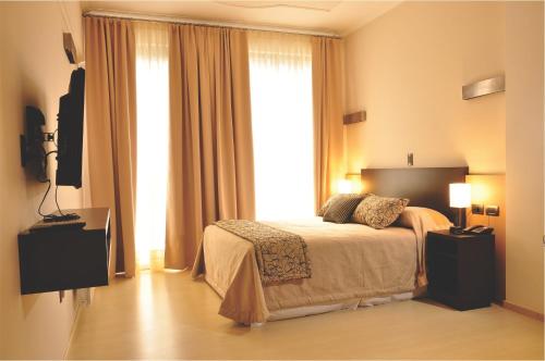 a bedroom with a bed and a large window at San Martin Plaza Hotel in Villa Elisa