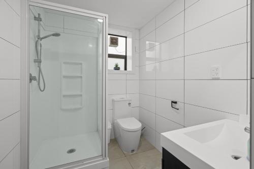 a white bathroom with a shower and a toilet at Waterfront location with estuary outlook and ocean beach access - sleeps 19 in Pukehina