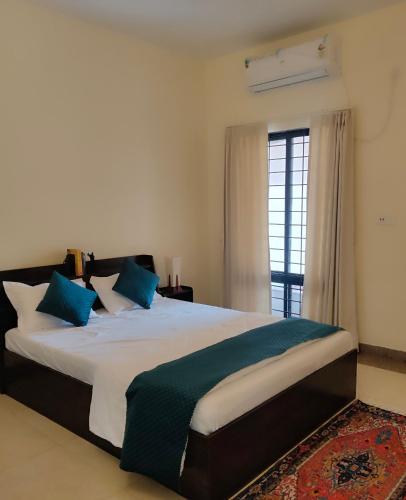 a bedroom with a large bed with blue pillows at Bhromor -A Pet-friendly Villa in Raichak