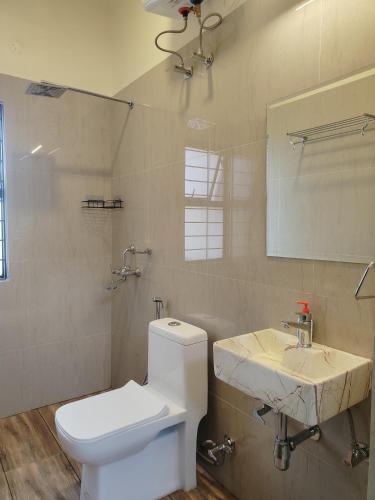 a bathroom with a white toilet and a sink at Bhromor -A Pet-friendly Villa in Raichak