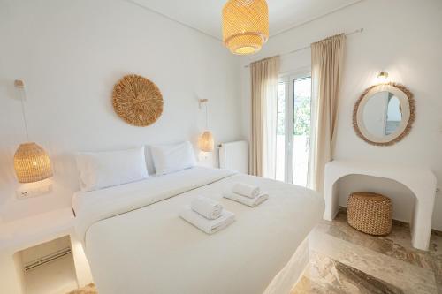 a white bedroom with a white bed and a mirror at The White Rose Hotel in Poros