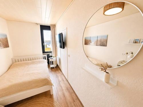 a bedroom with a bed and a mirror at Meerblick in der Meerzeitliebe Fehmarn in Fehmarn