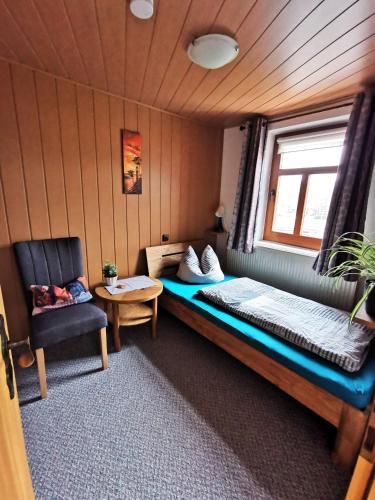 a small room with a bed and a chair at Pension Stepponat in Arnstadt