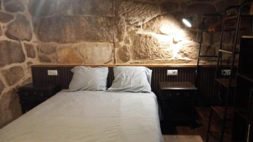 a bed in a room with a stone wall at A casa da Cernada in Rocas
