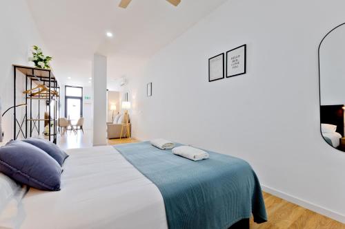 a white bedroom with a large bed with a blue blanket at Pato - Modern Apt - Near Bioparc by Río Turia Apartments in Valencia