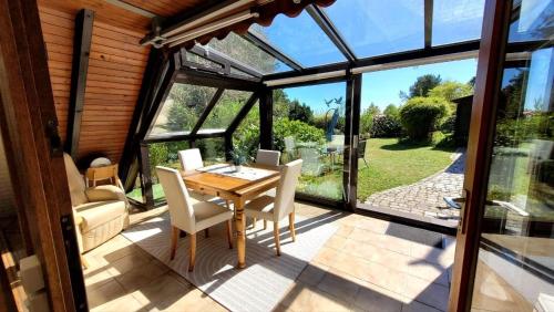 a conservatory with a wooden table and chairs on a patio at Chalet in Freilingen Blankenheim mit Seenähe mitten in der Natur in Blankenheim