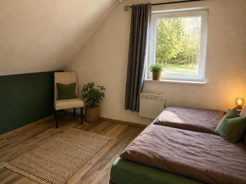 a bedroom with two beds and a window and a chair at Ferienhaus Pfefferminzhütte in Mildenau