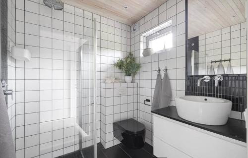 a white tiled bathroom with a sink and a toilet at Comfy Modern Guesthouse in Bankeryd