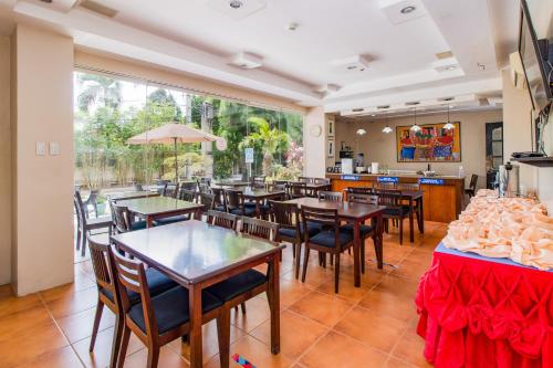 a restaurant with tables and chairs and a large window at Main Hotel and Suites Cebu in Cebu City