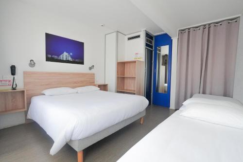 a bedroom with two beds and a tv on the wall at Hôtel Les Rives Bleues in La Grande Motte