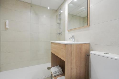 a bathroom with a sink and a toilet and a mirror at Hôtel Les Rives Bleues in La Grande Motte