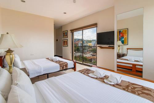 a hotel room with two beds and a balcony at Main Hotel and Suites Cebu in Cebu City
