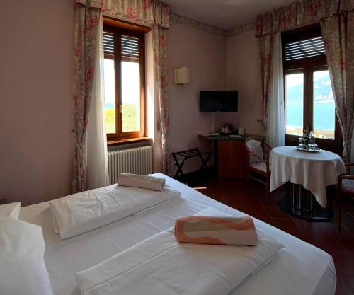 a bedroom with two beds and a table and windows at Villa Torre - Atmosfera Romantica in Brenzone sul Garda