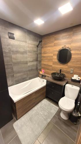 a bathroom with a tub and a toilet and a sink at Arena apartment in Panevėžys