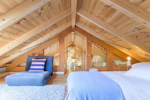 a bedroom with a large bed and a blue chair at Eclectic Monte Laginha Alentejo in Aldeia do Cano