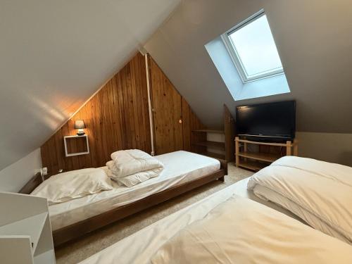 a attic bedroom with two beds and a skylight at chalet du mouflon au bec aigle in Le Lioran