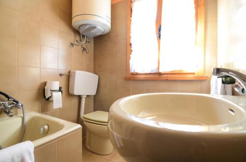 ein Badezimmer mit einer Badewanne, einem WC und einem Waschbecken in der Unterkunft Appartamenti Il Sogno in Campodolcino