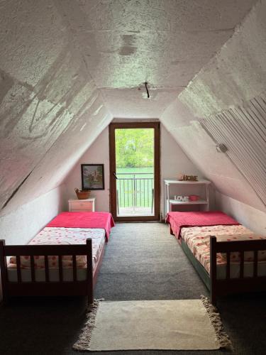 a attic room with two beds and a window at Ambijent house Patrijaha Pavla 22 in Železnička Stanica Ovčar Banja