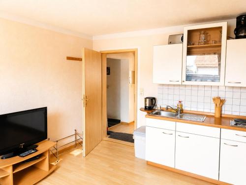 a kitchen with white cabinets and a flat screen tv at Einzelzimmer in Kelheim