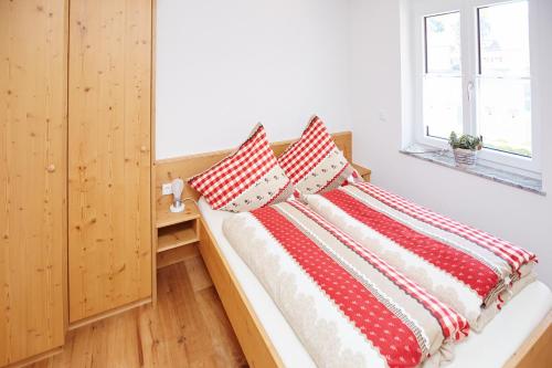 オーベルストドルフにあるOberstdorfer Bergwelt Herbersのベッドルーム1室(赤と白の枕が備わるベッド1台付)